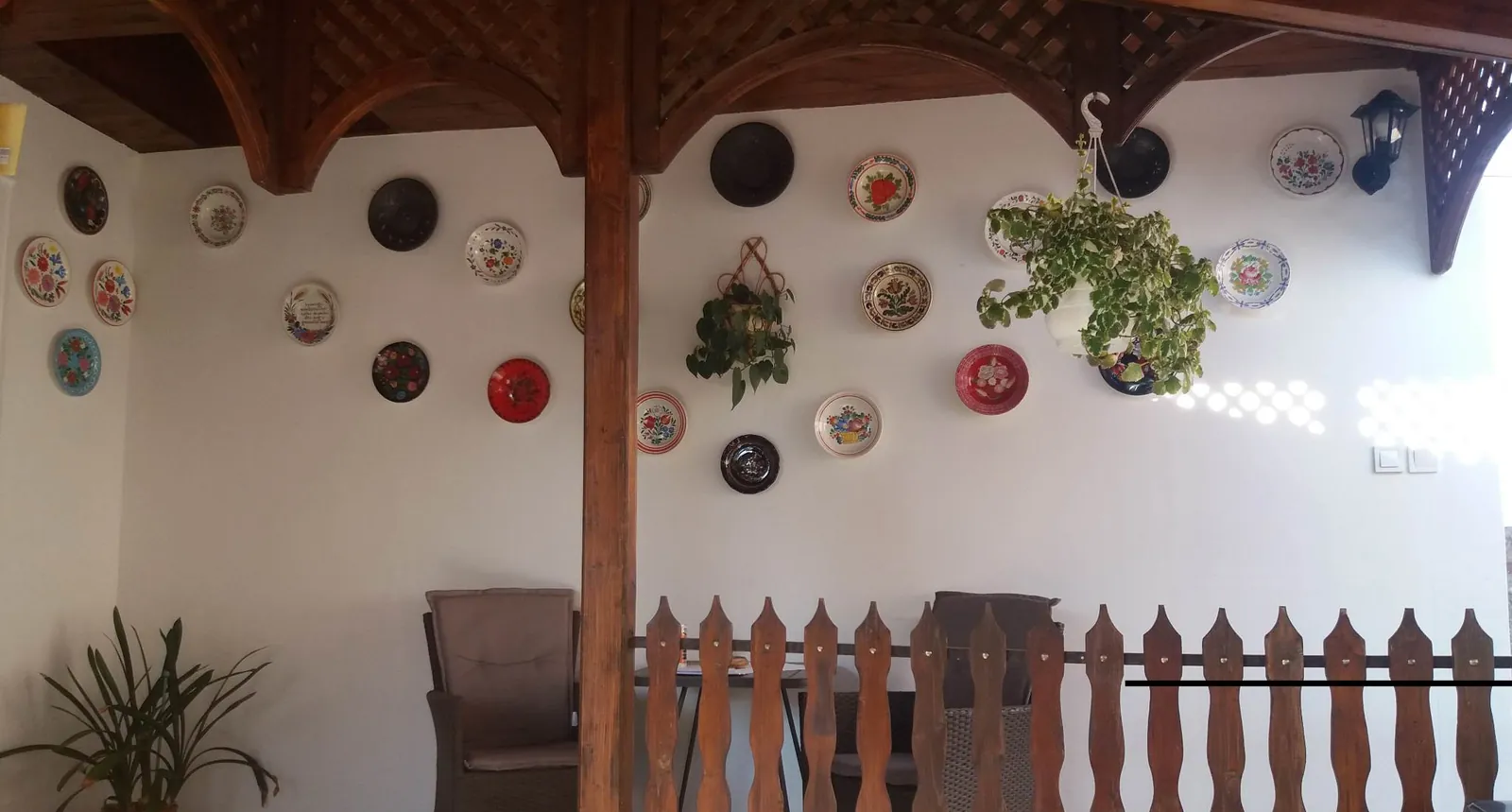 Festett népi falitányérok a tornác fehér falán