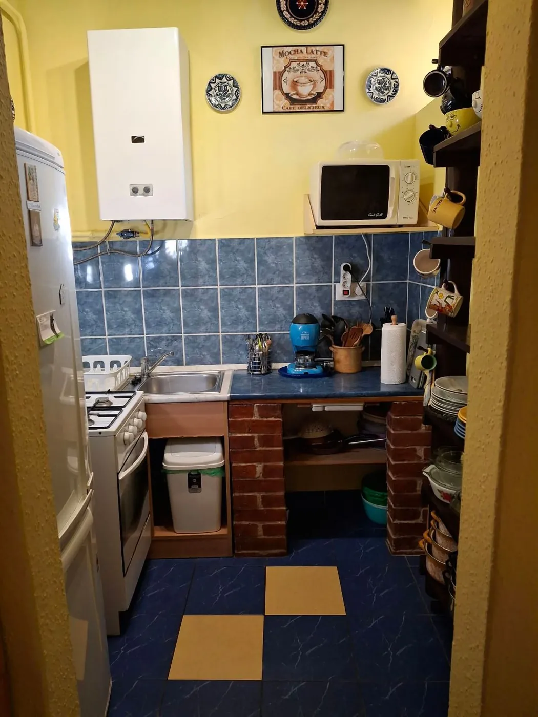 A konyha gáztűzhellyel, mikróval, hűtővel és edényekkel
